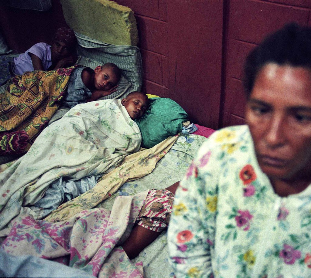 Josefina Marte, 43, right, watching her sons, Daniel and Martin Marte, and unidentified woman in the 15th Profecy´s Church in San Pedro de Macoris, 120 kilometers (75 miles) east of Santo Domingo, Dominican Republic, Saturday, June 8, in 2002.  After a week of heavy rains in eastern Dominican, that was hit the hardest and at least 170 families were staying in shelters set up in churches and schools (AP Photo/Miguel Gomez)
