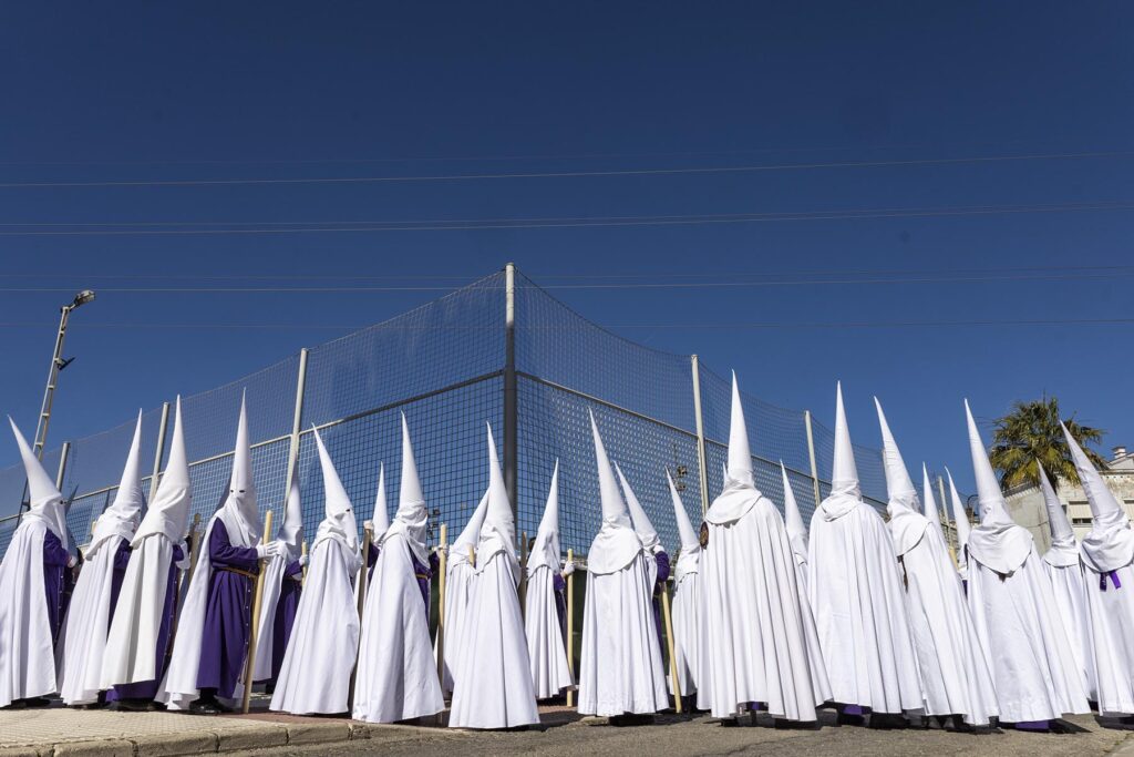 Un grupo de penitentes al sol esperan la salida de la procesiónón de El Gran Poder durante la Semana Santa 2026 en la Bahía de Cádiz en San Fernando, Cádiz, España.