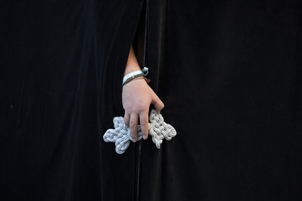 Detalle de la mano de un cargador o costalero saliendo de debajo del paso de La Soledad en El Puerto de Santa María en Cádiz, España durante la Semana Santa 2026 en la Bahía de Cádiz.